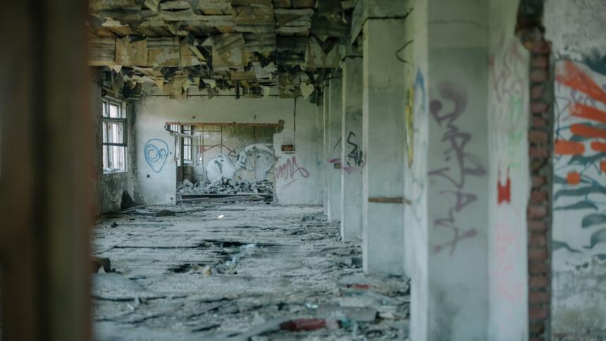 Ein stark verwüsteter Betonrohbau von innen, beschmiert mit Graffiti