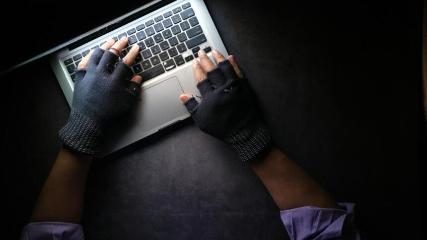 Zwei Hände mit Fingerlingen auf einer Tastatur, von oben fotografiert