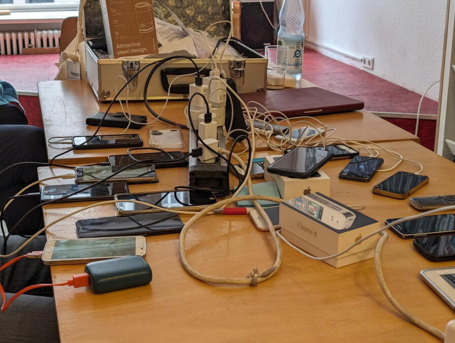 Ein Tisch liegt voller Smartphones und Kabel