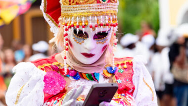 Maskierte Person auf Karneval mit Handy.