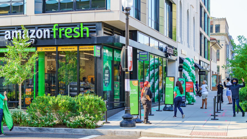 Foto von der Außenseite eines modern aussehenden Supermarktes mit dem Schriftzug "Amazon Fresh" in grünen Leuchtbuchstaben
