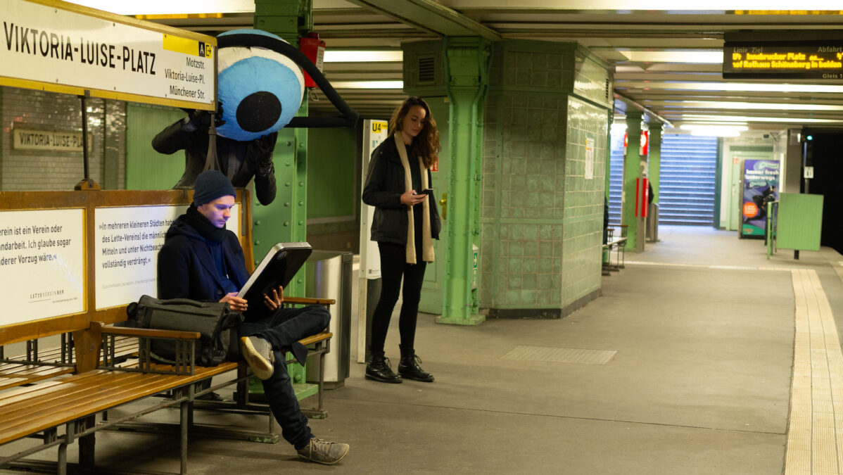 Ein übergroßes Auge schaut einem menschen aufs Handy