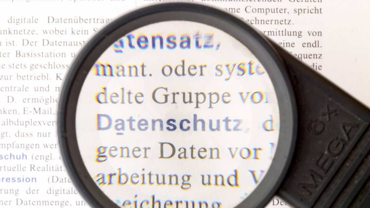 Lupe schaut auf Buch, in dem Datenschutz als Wort steht