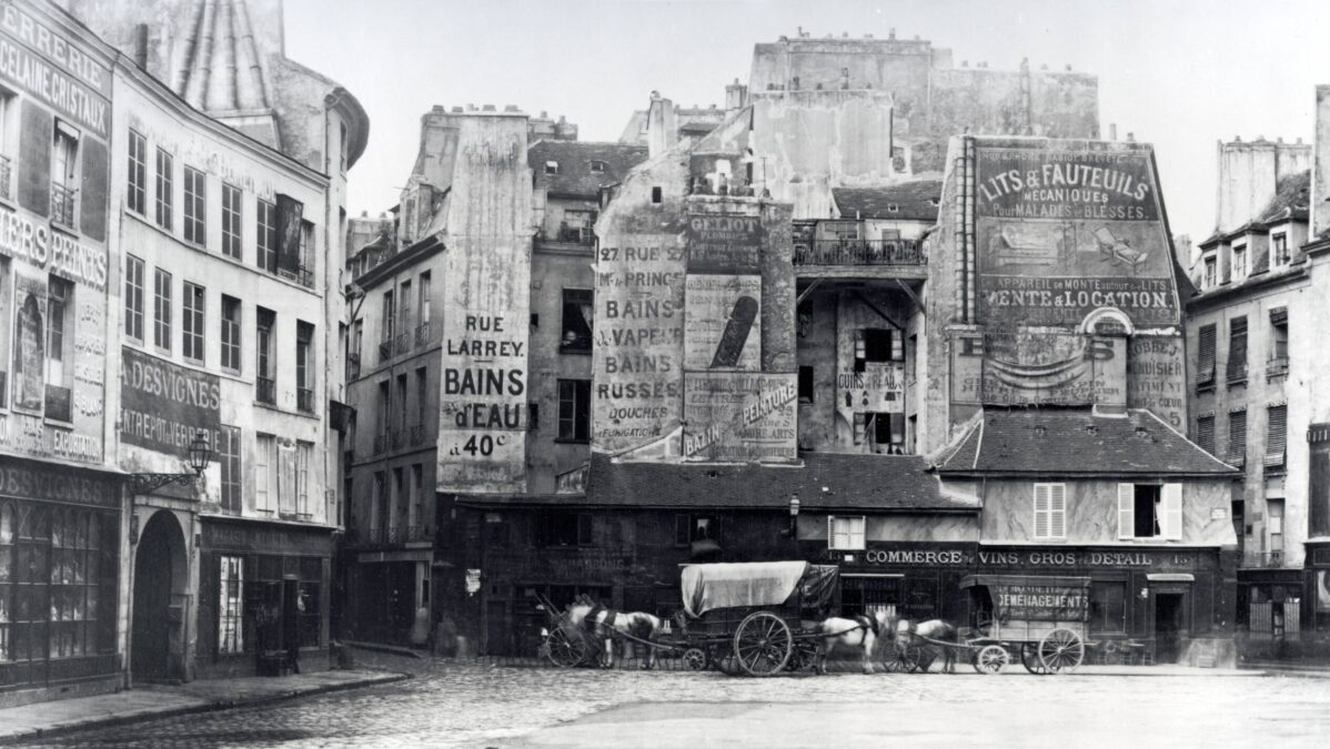 Historisches Foto eines Platzes in Paris, an den Wänden sehr viele unterschiedliche Werbeaufschriften