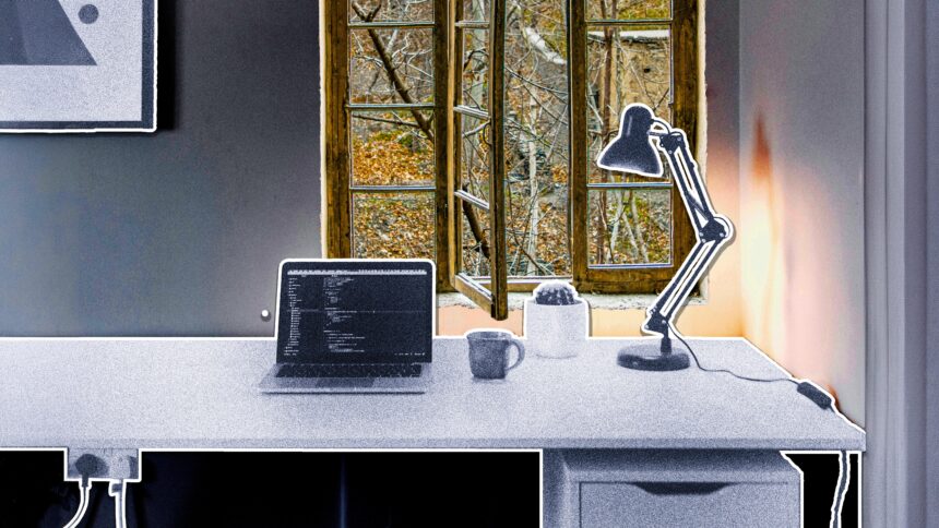 ein Schreibtisch mit Laptop und Tischlampe, dahinter ein offenes Fenster mit Blick in den Wald