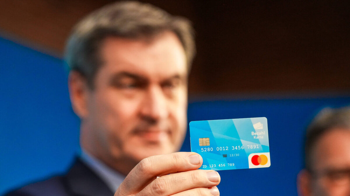 Markus Söder hält eine Bezahlkarte in die Kamera