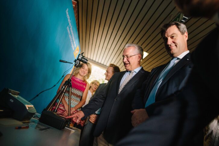 Zwei Männer in schwarzen Anzügen schauen von oben auf ein technisches Gerät