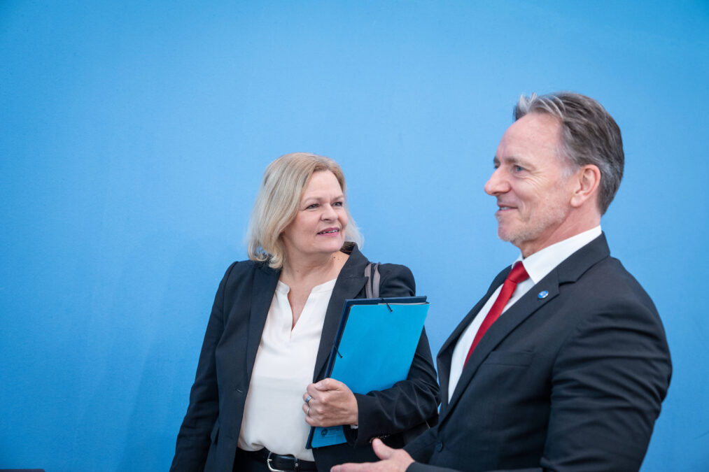 Nancy Faeser und Holger Münch vor einem blauen Hintergrund.