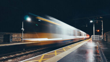 ein Zug rast so schnell bei Nacht durch einen Bahnhof (bewegungsunscharf)
