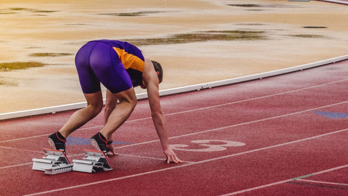 Ein Läufer steht im Startblock einer Rennstrecke bereit zum Losrennen