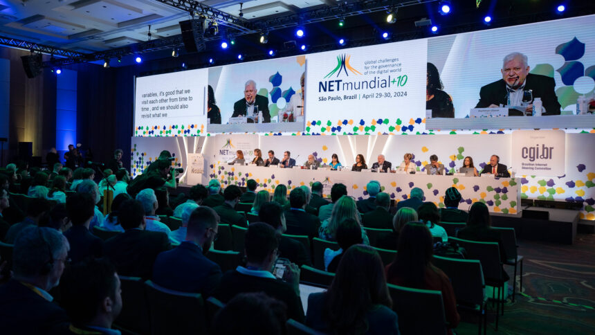 Foto von der Eröffnung von NETmundial+10. Zu sehen sind mehr als zehn Menschen, die auf einer breiten Bühne sitzen und der Zuschauerraum