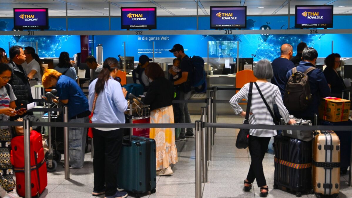 Menschen stehen vor einem Check-In-Schalter.