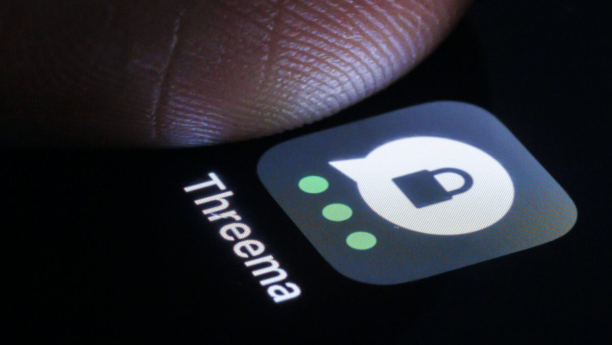 Ein Daumen drückt auf ein Threema-Logo