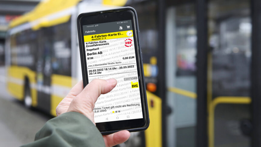 Ein Smartphone mit einem digitalen BVG-Ticket, dahinter ein wartender Bus.