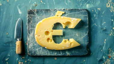 A piece of cheese with holes in the shape of the euro symbol, lying on a blue board with a small cutting knife next to it.