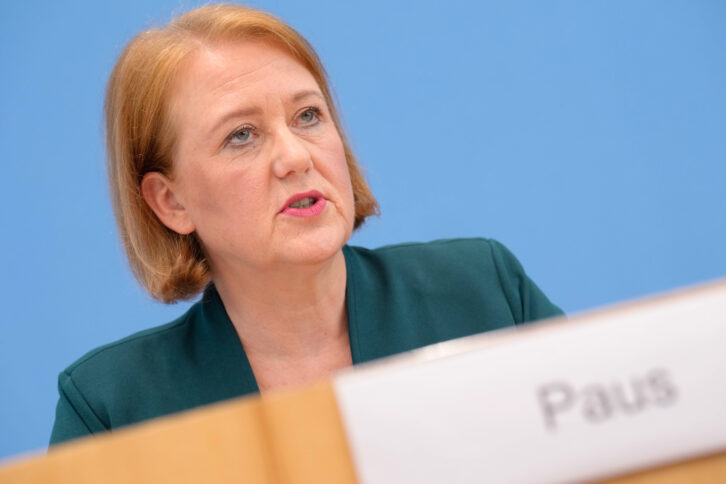 Frau im grünen Blazer hinter einem Pult, von schräg unten fotografiert