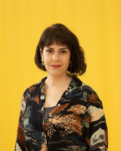 A woman with dark hair in front of a yellow background