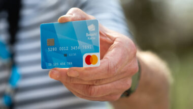 Eine Hand hält eine bayerische Bezahlkarte in die Kamera. Sie ist hellblau.