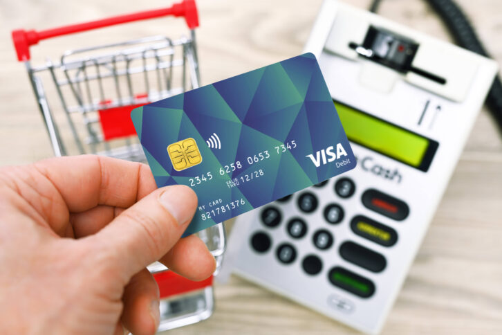 Bezahlkarte, im Hintergrund ein Einkaufswagen und ein EC-Karten-Terminal