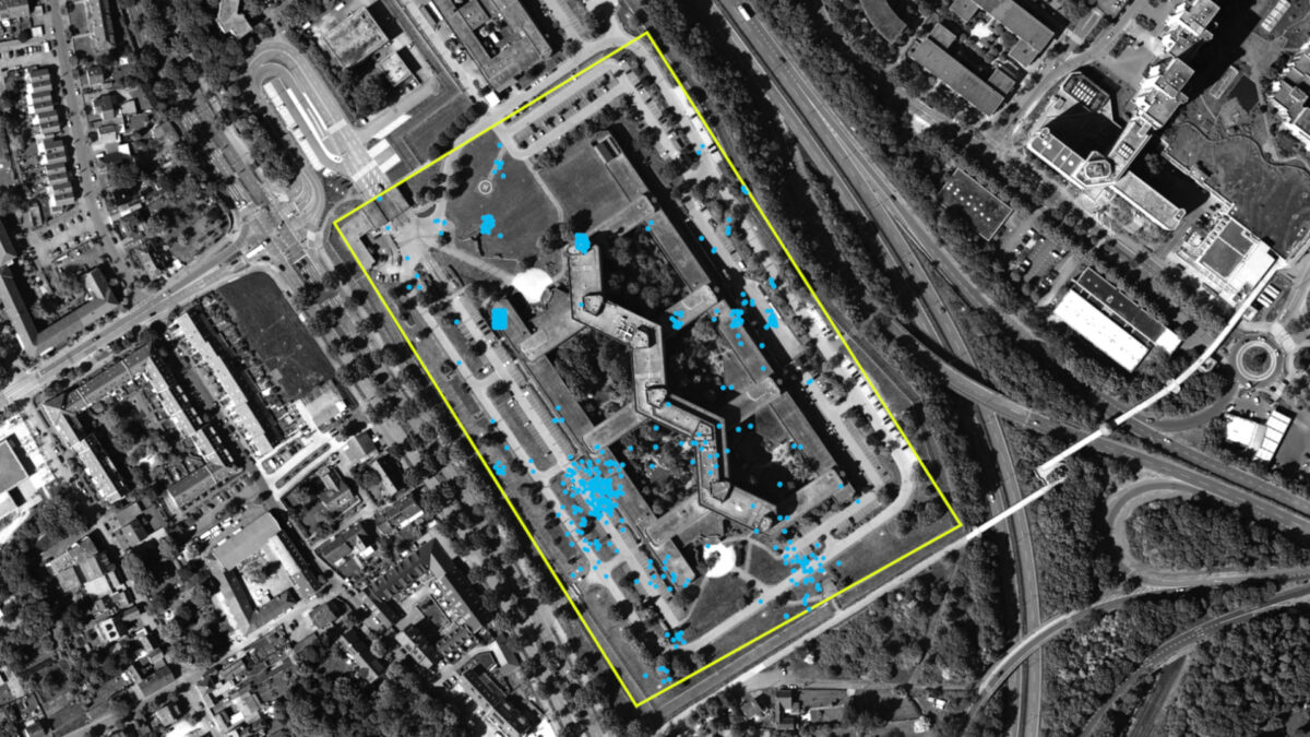 Satellitenaufnahme in Graustufen zeigt den Hauptsitz des Bundesverfassungsschutzes. Das Areal ist mit einem gelben Umriss hervorgehoben. Blaue Punkte sind im Areal sichtbar.