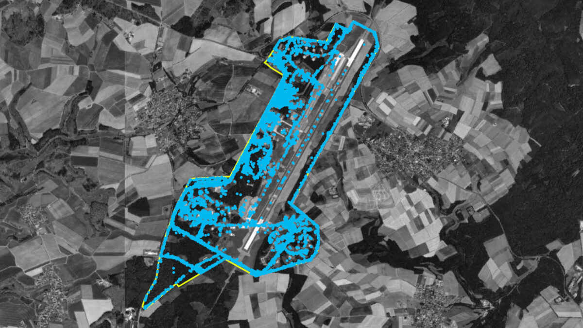 Satellitenaufnahme in Graustufen zeigt den Fliegerhorst Büchel. Das Areal ist mir einem gelben Umriss hervorgehoben. Blaue Punkte sind im Areal sichtbar.