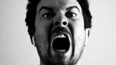 Frontal aufgenommenes schwarz-weiß-Foto eines Mannes, der wütend schreit.