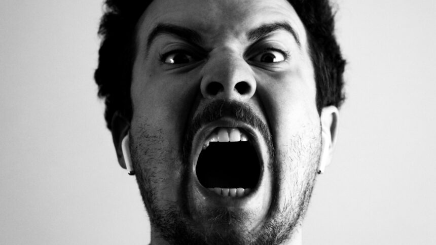 Frontal aufgenommenes schwarz-weiß-Foto eines Mannes, der wütend schreit.