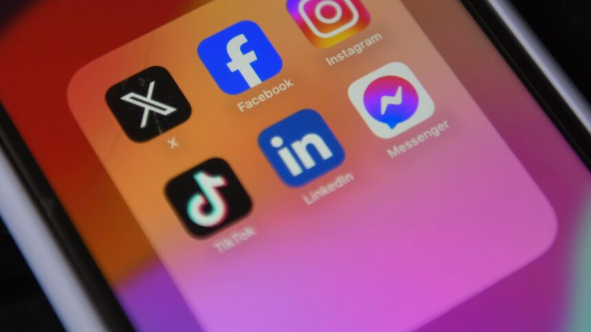 Smartphone-Bildschirm zeigt Icons von Facebook, X, Insta und TikTok.