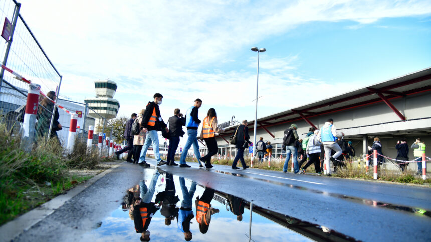 Menschen überqueren eine Straße am Flughafen Tegel