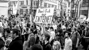 Menschen demonstrieren, in der Mitte ein Schild mit der Aufschrift "Don't f*ck our Internet"