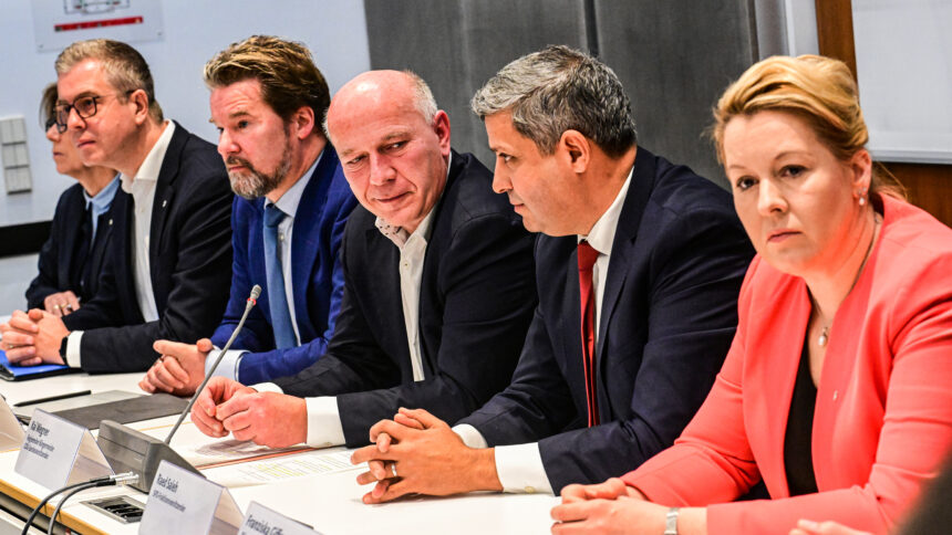 Sechs Mitglieder der schwarz-roten Landesregierung an einem langen Tisch mit Mikrofonen zur Pressekonferenz