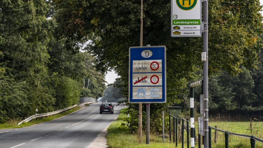 Grenze zwischen Deutschland und den Niederlande. Erkennbar an einem Schild mit geltenden Geschwindigkeitslimits und der Bushaltestelle "Landesgrenze"