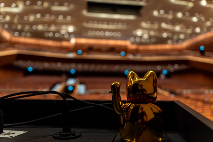 Eine Winkekatze auf einem Rednerpult in einem großen Vortragssaal