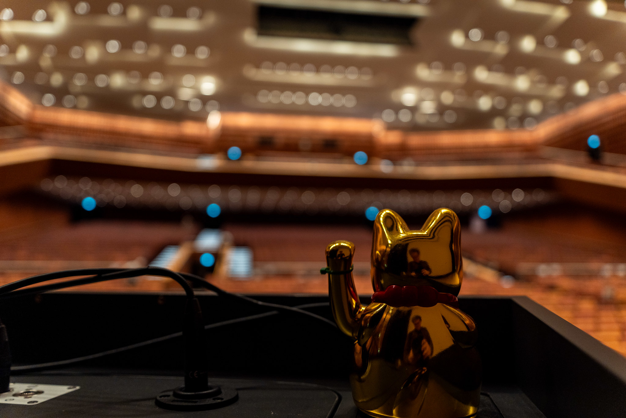 Eine Winkekatze auf einem Rednerpult in einem großen Vortragssaal