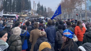 Menschen stehen auf einer Straße, es ist eine Europafahne zu sehen.