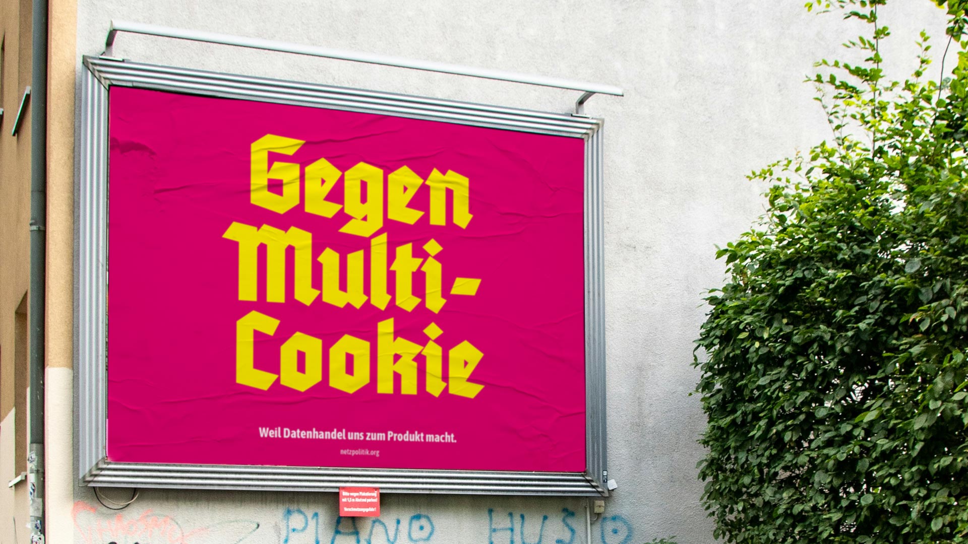 Hauswand mit Graffiti und Plakatwand mit Großplakat „Gegen Multi-Cookie“