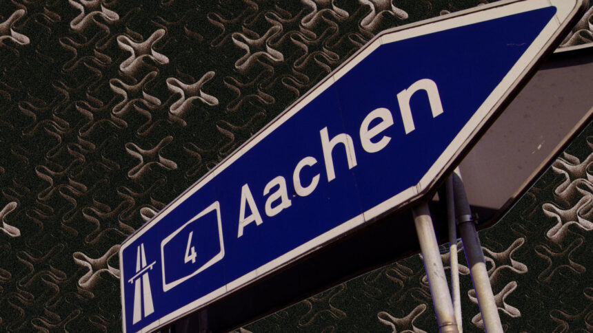 AUtobahnschild, auf dem "A4 Aachen" steht, im Hintergrund viele Kreuze.