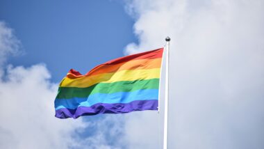 Regenbogenflagge vor blauem Himmel