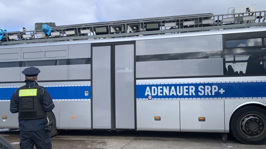 Polizist steht vor einem Fahrzeug, das wie ein Polizeibus aussieht.