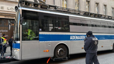 Polizeiähnlicher Bus mit Aufschrift "Adenauer" wird abgeschleppt.