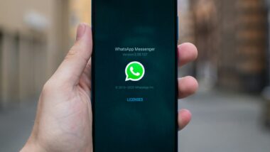 Eine Hand hält ein Telefon, auf dem das WhatsApp-Logo zu sehen ist