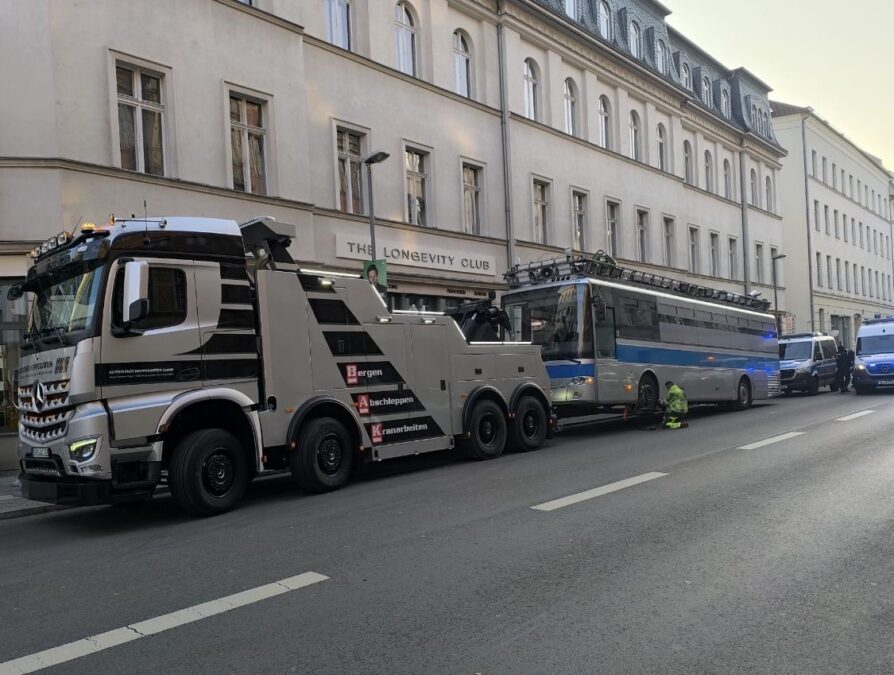 Großes Abschleppfahrzeug schleppt einen Bus ab.