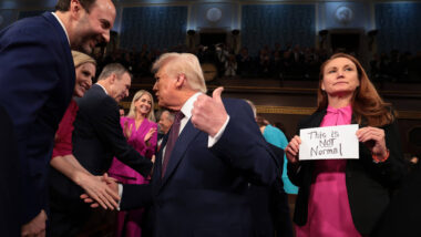 Trump schüttelt Hände im US-Congress, hinter ihm hält jemand ein Schild "This is not normal".