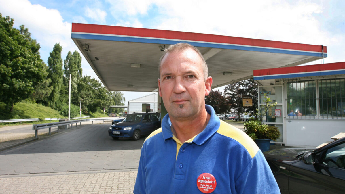 Mann steht vor Tankstelle
