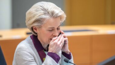 Fotografie der EU-Kommissionspräsidentin Ursula von der Leyen wie sie mit Hand vor dem Mund am Handy telefoniert.