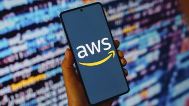 Smartphone mit Aufschrift AWS, im Hintergrund verschwommene Schrift