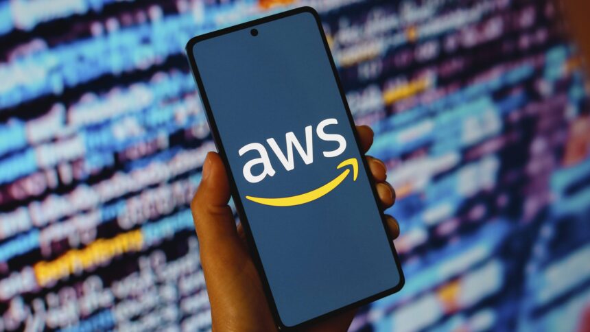Smartphone mit Aufschrift AWS, im Hintergrund verschwommene Schrift