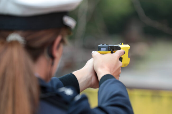 Polizistin zielt mit einem gelben Taser auf ein unsichtbares Ziel