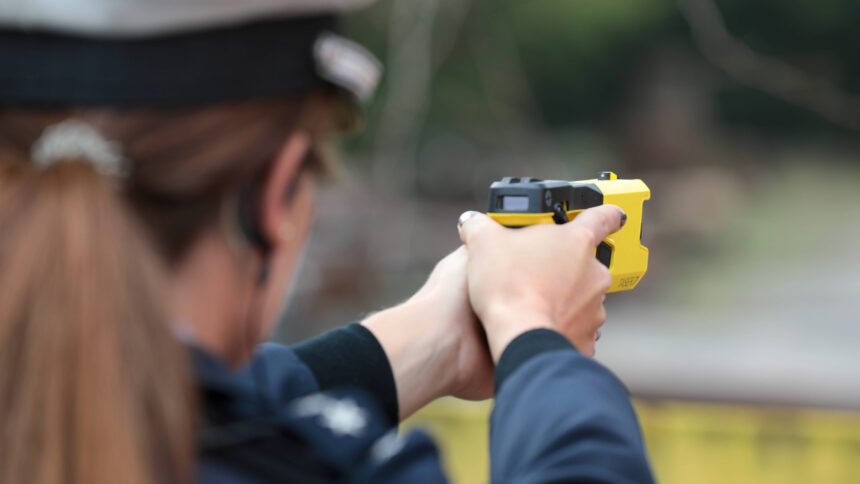 Polizistin zielt mit einem gelben Taser auf ein unsichtbares Ziel