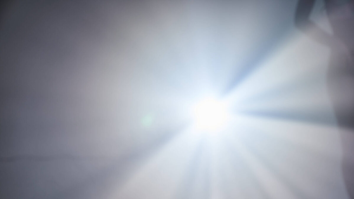 Man sieht ein blendendes Licht, am Rand die Silhoutte eines Menschen